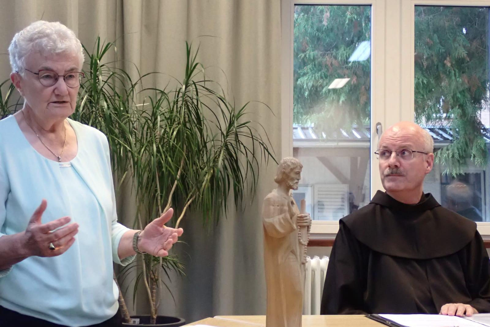 Links steht eine Frau, rechts sitzt ein Mann