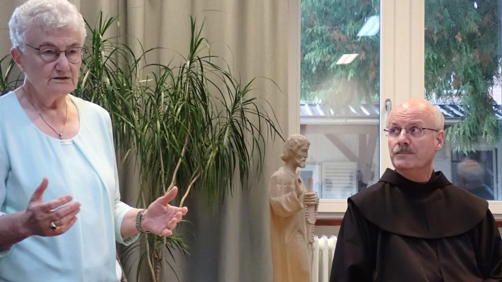 Links steht eine Frau, rechts sitzt ein Mann